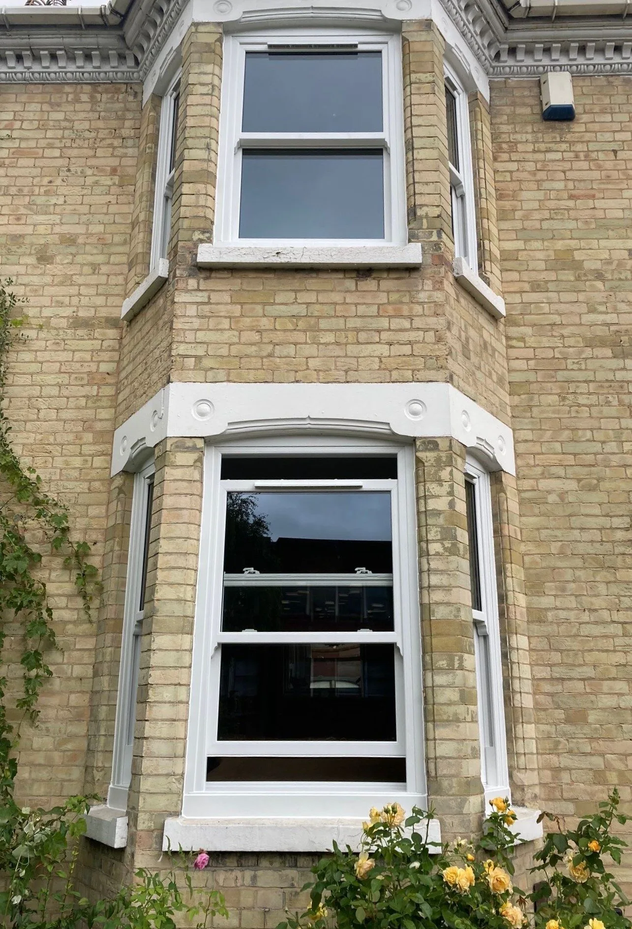 White sliding sash windows in a two-storey yellow-brick bay
