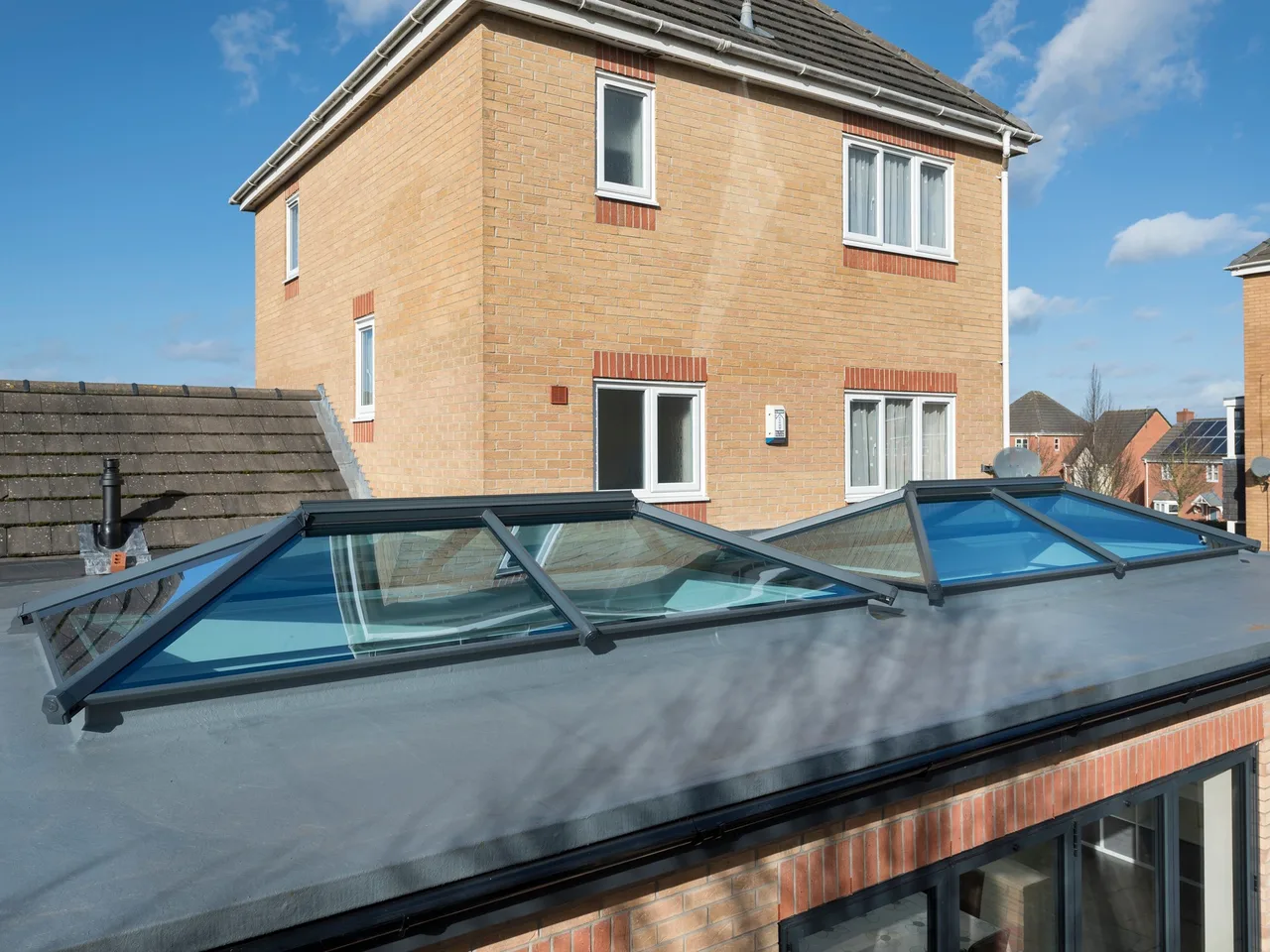 Grey roof lantern on the flat roof of a brick house extension