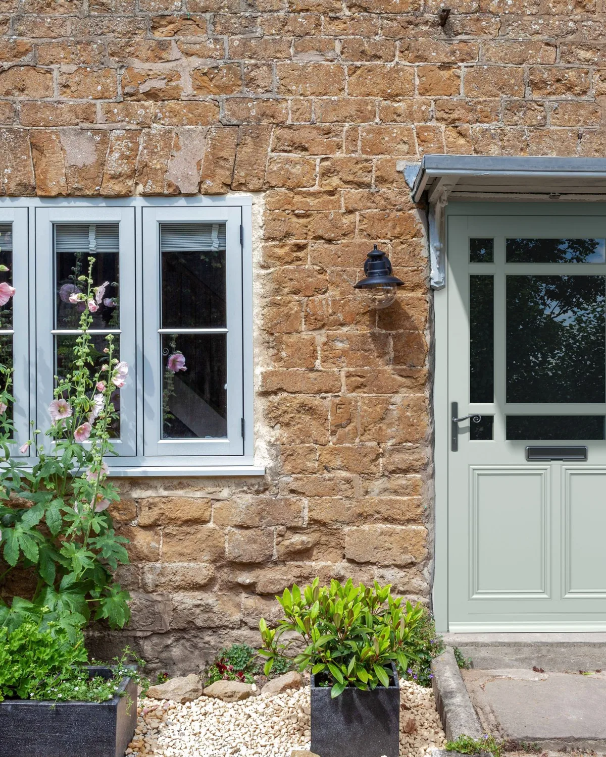 Stone cottage with a sage green door and white double glazed windows