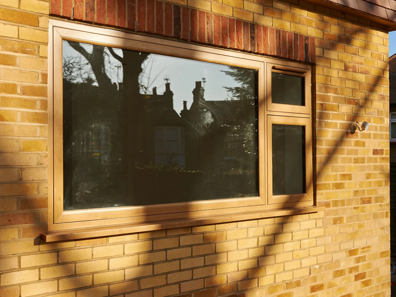 Walnut woodgrain flush casement window set into a honey-coloured stone wall