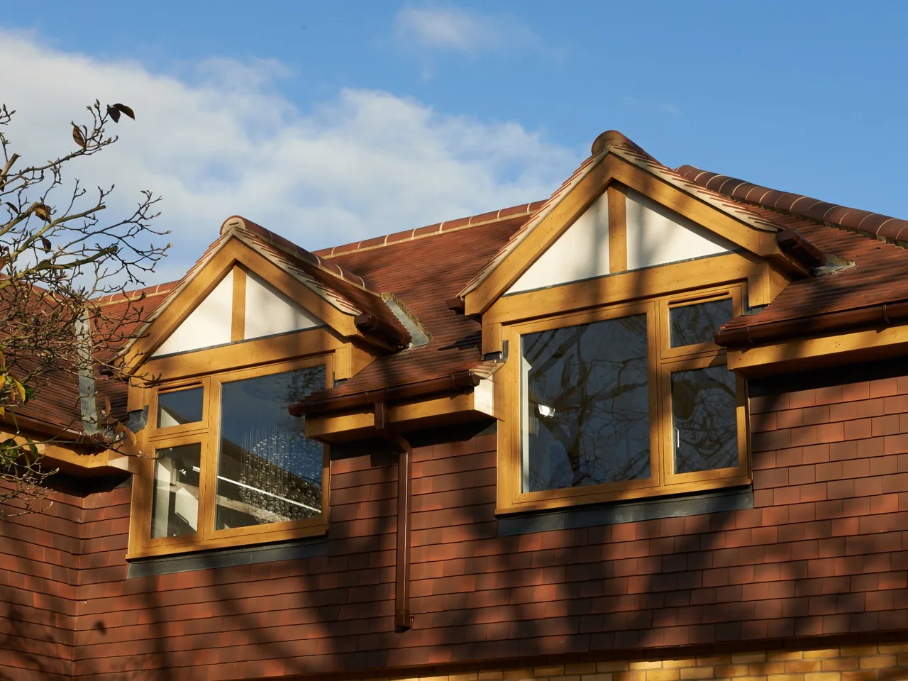Oak-effect flush casement windows in two timber-clad dormers on a tiled roof