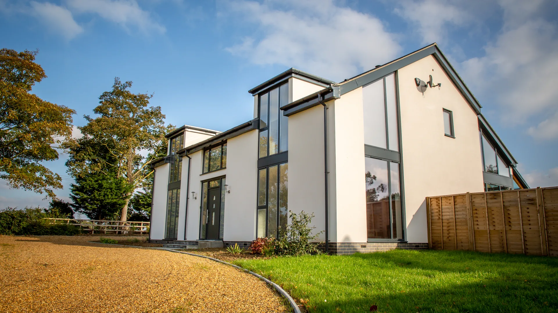 Modern white-rendered detached home with anthracite grey aluminium casement windows and full-height glazing