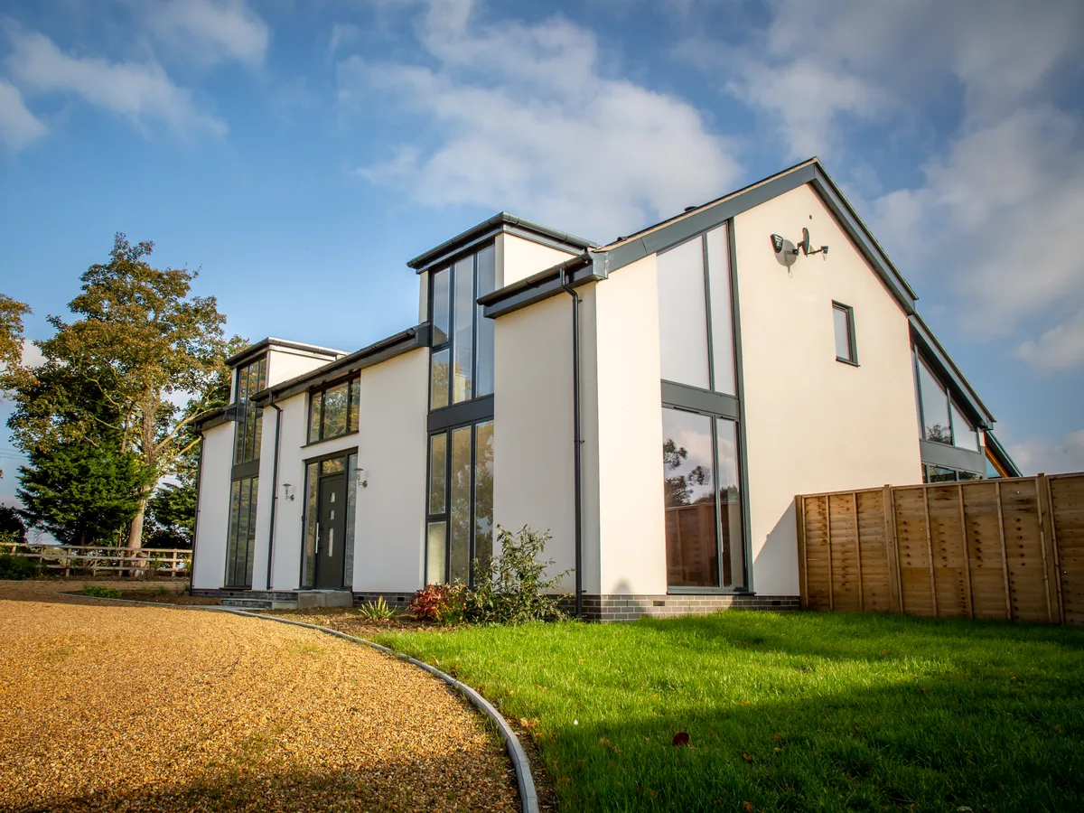 Modern white-rendered detached home with anthracite grey aluminium casement windows and full-height glazing