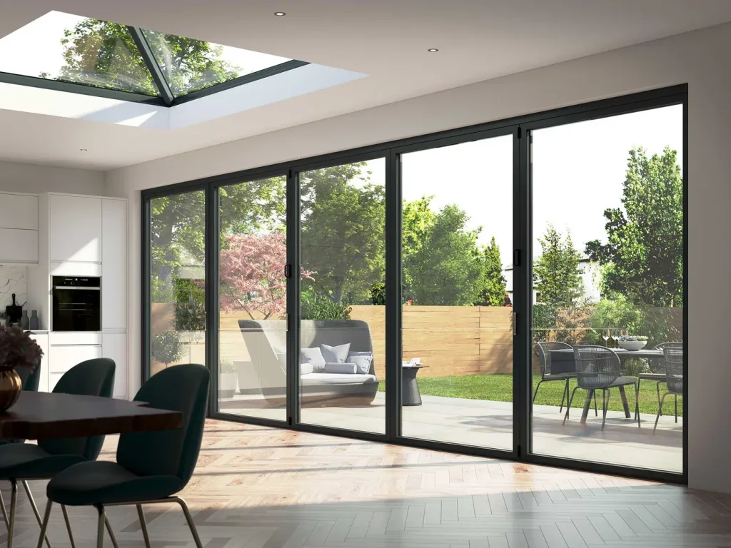 Dark grey glass doors closed across a dining room wall, looking onto a landscaped garden