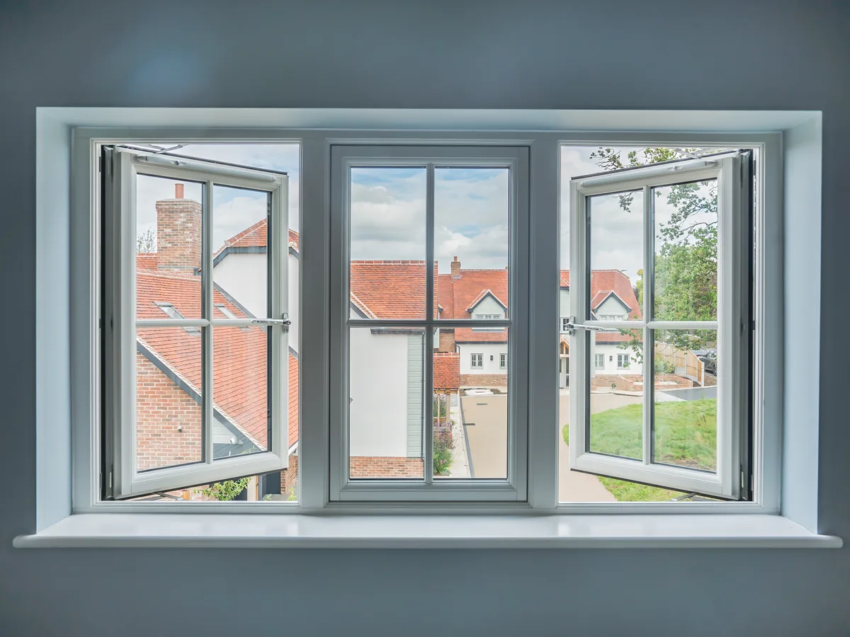 White three-pane casement window with Georgian bars and both side sashes open, seen from inside