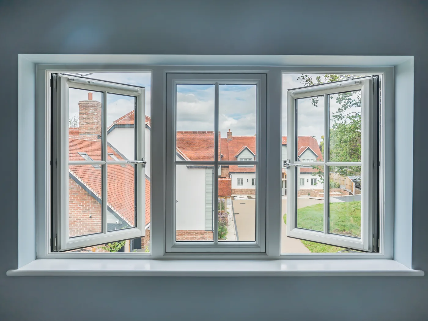 White three-pane casement window with Georgian bars and both side sashes open, seen from inside