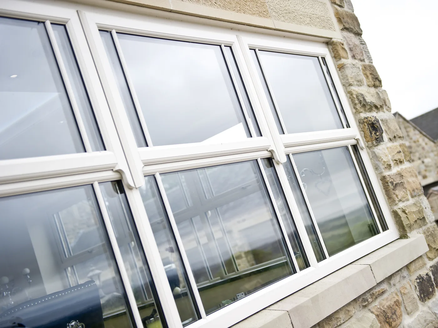 White sash horn windows with glazing bars in a stone house, with stone outbuildings behind