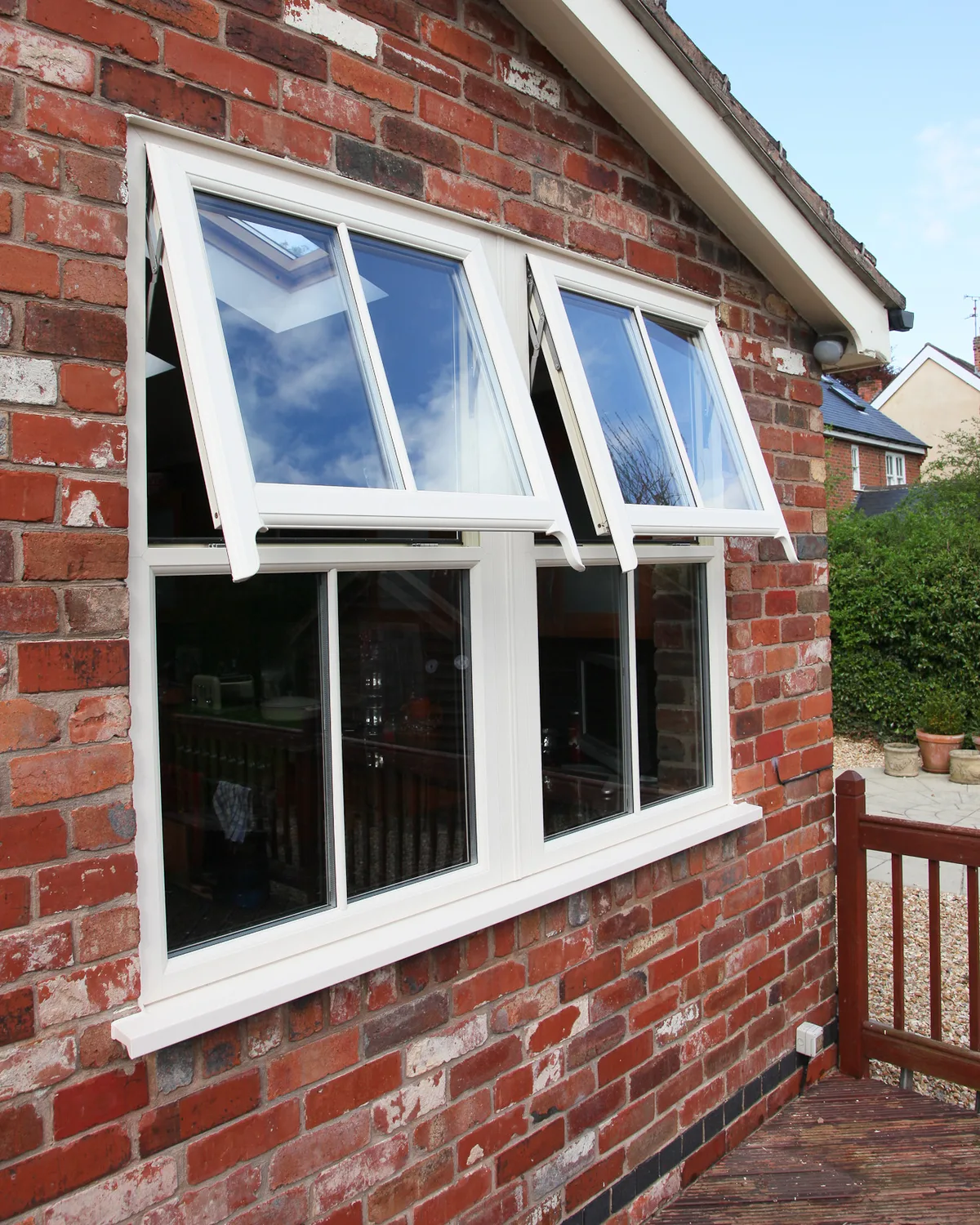 White sash horn windows with both top vents open in a red brick gable wall