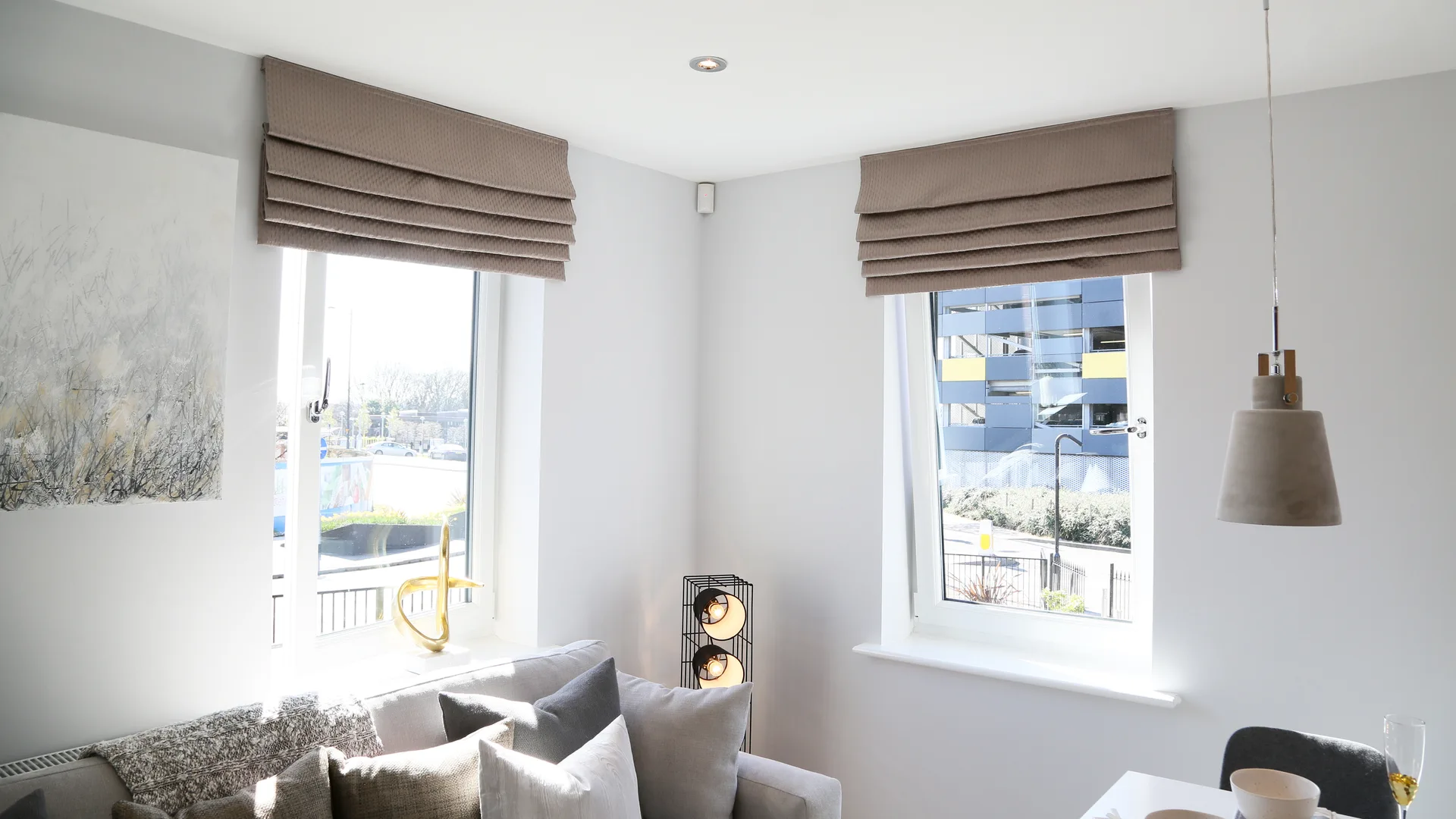 Bright living room with two white tilt and turn windows under roman blinds, one sash open inward