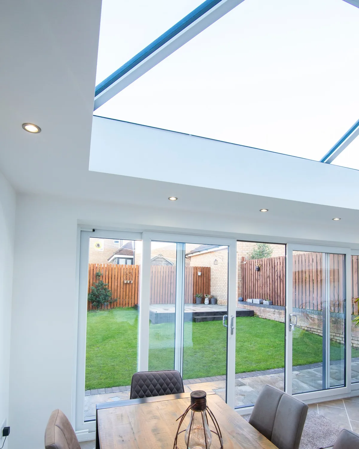 Roof lantern above a dining table, sunlight streaming into an open-plan kitchen with bifold doors